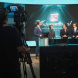 Een lege talkshowstudio met een desk en stoelen onder felle studiolampen