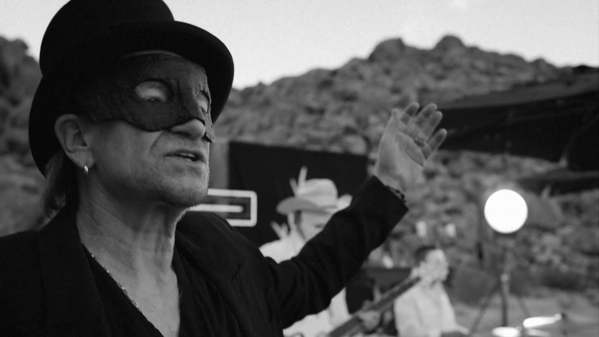 Bono met hoge hoed en masker in de woestijn in de clip van The Greatest Show On Earth
