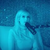 Twee mensen in gesprek aan podcastmicrofoons in een blauw verlichte studio